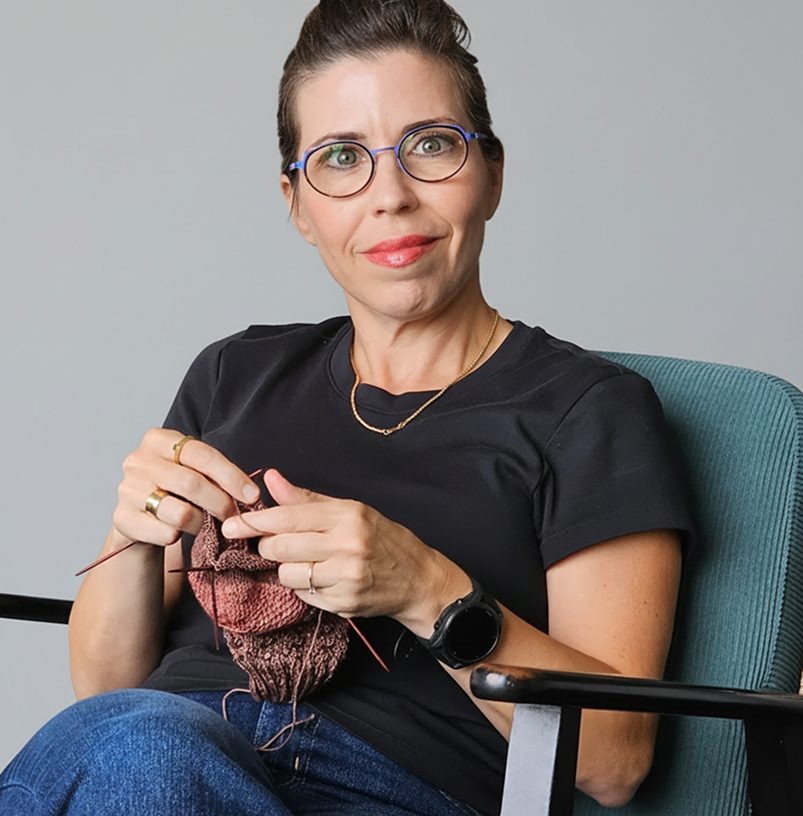 Xen Mendelsohn Aderka knitting in an armchair